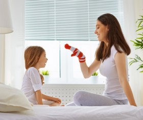 Mother sitting in bed playing with daughter Stock Photo 01