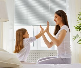 Mother sitting in bed playing with daughter Stock Photo 02
