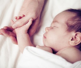 Sleeping baby holding his father hand Stock Photo