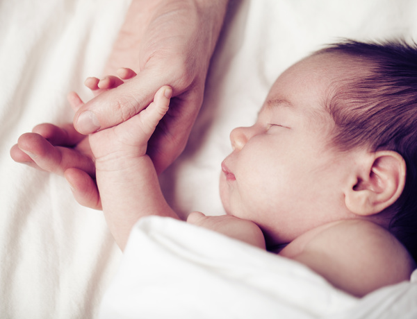 Sleeping baby holding his father hand Stock Photo