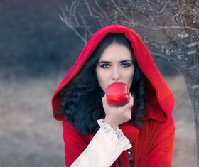 Woman wearing red cloak holding a red apple Stock Photo