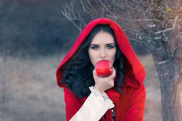 Woman wearing red cloak holding a red apple Stock Photo
