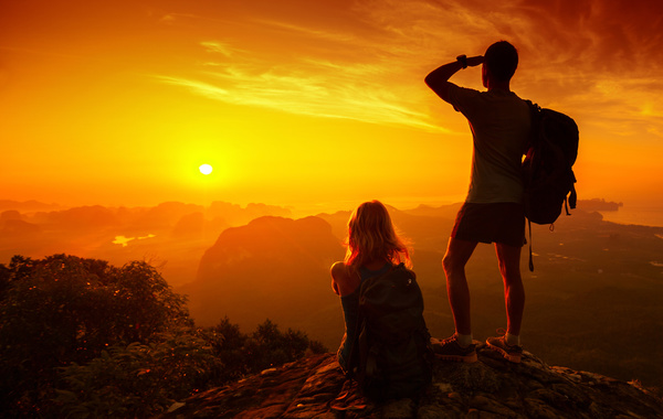 Young Lovers on the top of the mountain looking at sunrise Stock Photo