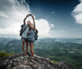 Young couple taking pictures on the mountain top Stock Photo