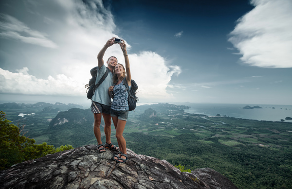 Young couple taking pictures on the mountain top Stock Photo