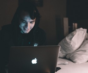 Young man sitting in bed using laptop Stock Photo