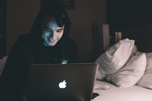Young man sitting in bed using laptop Stock Photo