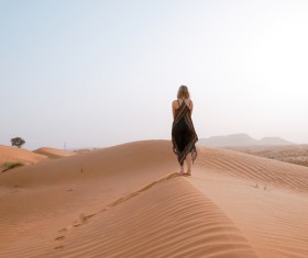 woman walking on dunes desert Stock Photo