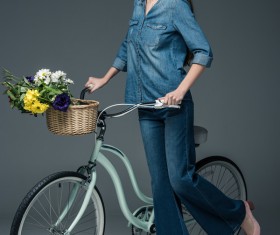 Beautiful woman wearing denim suit pushes bicycle Stock Photo 01