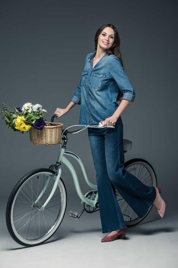 Beautiful woman wearing denim suit pushes bicycle Stock Photo 01