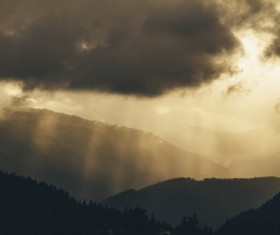 Black clouds and sun rays on mountain Stock Photo