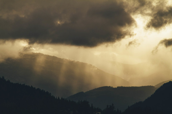 Black clouds and sun rays on mountain Stock Photo