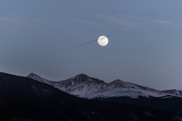 Bright moon above snowy mountain range Stock Photo