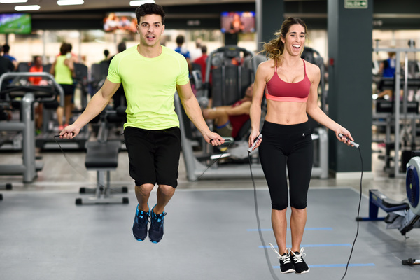 Couple doing jump rope exercises in gym Stock Photo