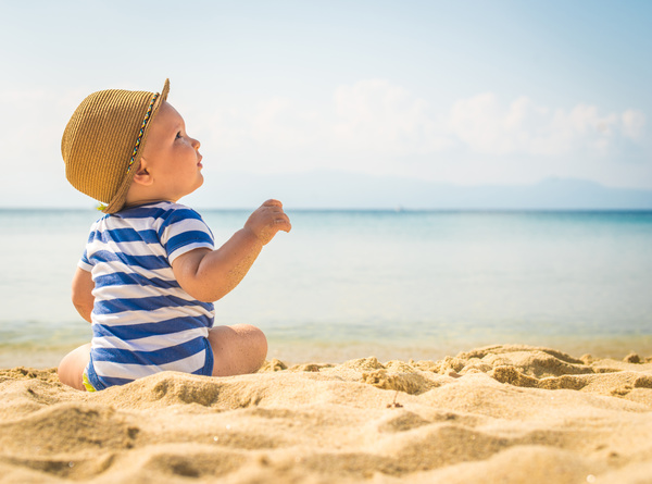 Cute little boy sitting on the beach Stock Photo