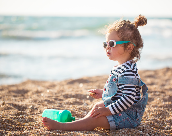 Cute little girl sitting on the beach Stock Photo