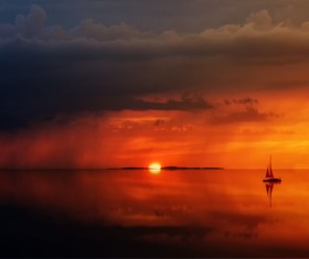 Dark red sunset shines on calm lake with boats Stock Photo