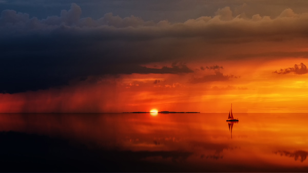 Dark red sunset shines on calm lake with boats Stock Photo