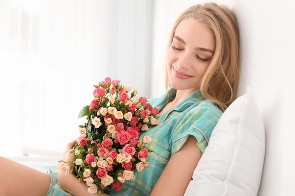 Girl sitting in bed holding a rose flower Stock Photo 02