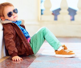 Little boy with sunglasses sits on the floor Stock Photo