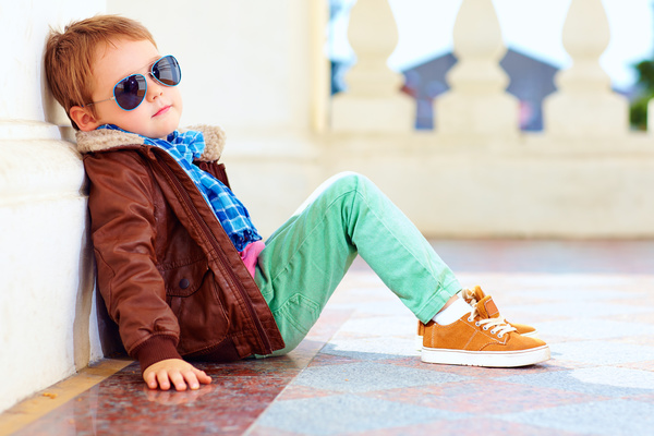 Little boy with sunglasses sits on the floor Stock Photo