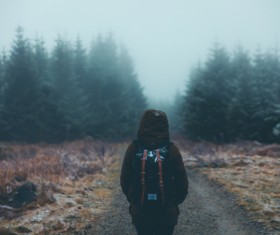 Lonely backpacker walking on misty pathway Stock Photo