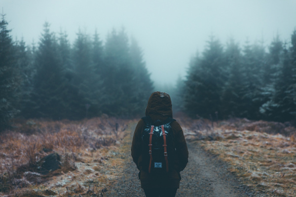 Lonely backpacker walking on misty pathway Stock Photo