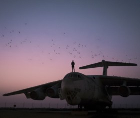 Man performing standing on airplane roof at dusk Stock Photo