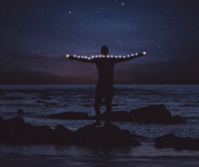 Man posing with lights on starry night beach Stock Photo