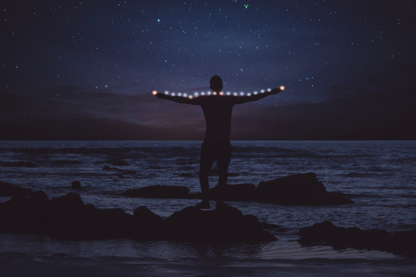 Man posing with lights on starry night beach Stock Photo
