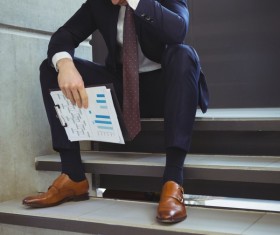 Man sitting on steps hands holding business report Stock Photo