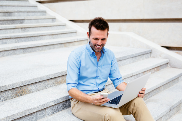 Man using laptop while sitting on outdoor steps Stock Photo