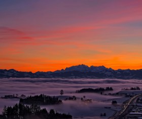 Thick fog covering mountain town at dusk Stock Photo