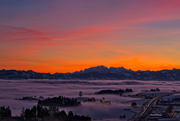 Thick fog covering mountain town at dusk Stock Photo