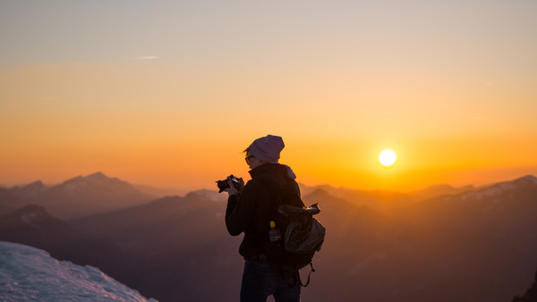 Tourist enjoying frozen mountain scene at dusk Stock Photo