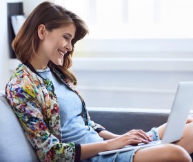 Woman sitting on sofa using laptop Stock Photo