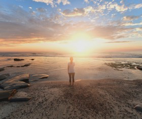Woman standing on the beach watching the sunrise Stock Photo