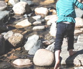 Young kid playful on rocky lake Stock Photo