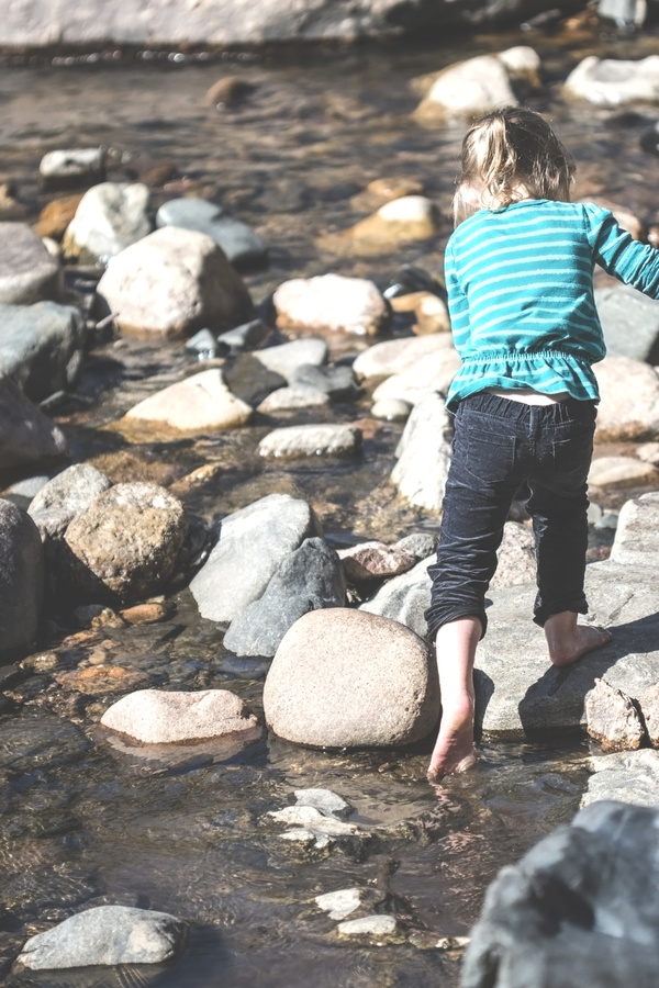 Young kid playful on rocky lake Stock Photo