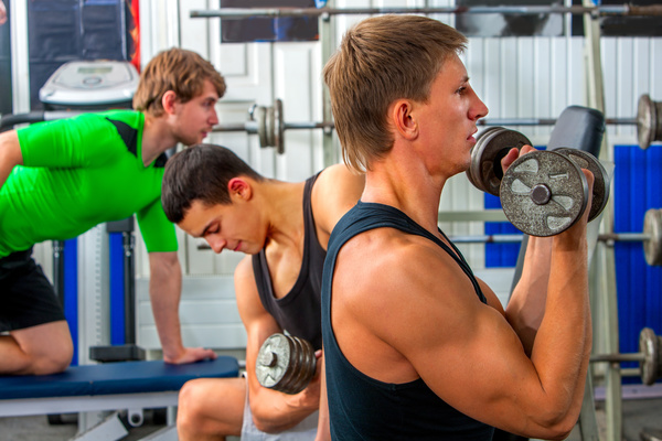 Young man doing arm exercise in gym Stock Photo