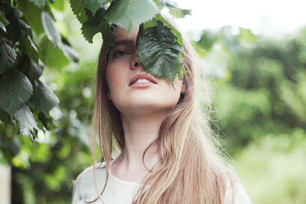 blonde woman posing with leaf hiding face Stock Photo