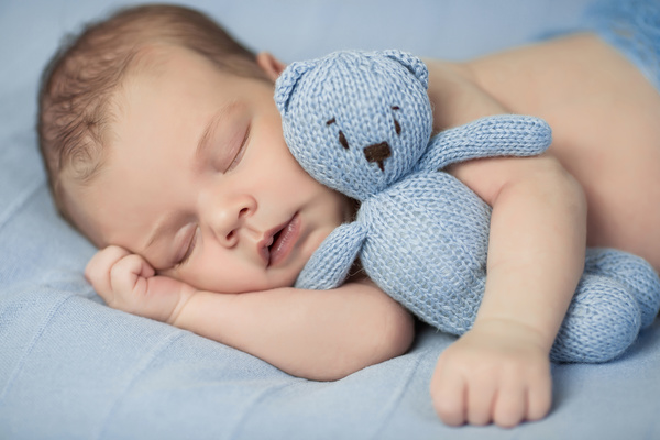 Baby holding knitted bear sleeping Stock Photo 01