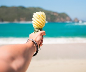 Closeup man holding pineapple on beach Stock Photo