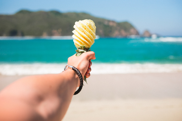Closeup man holding pineapple on beach Stock Photo