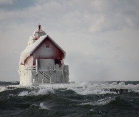 Frozen lighthouse on wavy beach Stock Photo