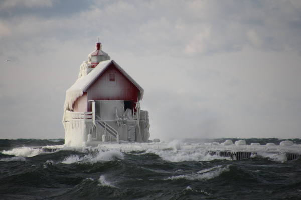 Frozen lighthouse on wavy beach Stock Photo