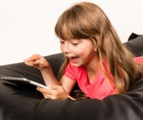 Little girl playing Tablet PC on inflatable chair Stock Photo