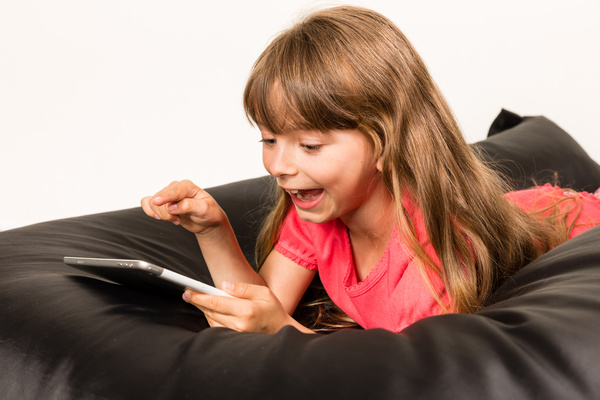 Little girl playing Tablet PC on inflatable chair Stock Photo