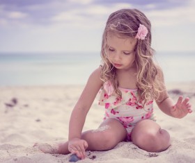 Little girl playing with sand on the beach Stock Photo