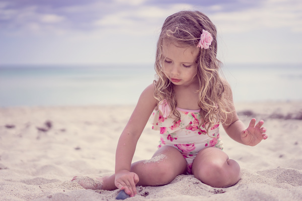 Little girl playing with sand on the beach Stock Photo